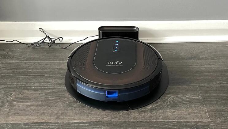Eufy RoboVac G30 Hybrid on its charging stand on a wooden floor